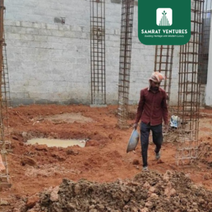 Construction workers laying Plain Cement Concrete (PCC) and footings over a prepared base at the Kogilu residential project.