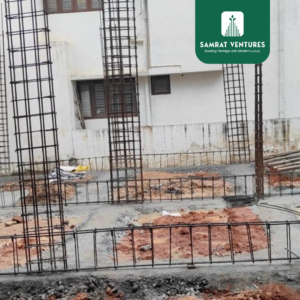 Construction workers laying Plain Cement Concrete (PCC) and footings over a prepared base at the Kogilu residential project.